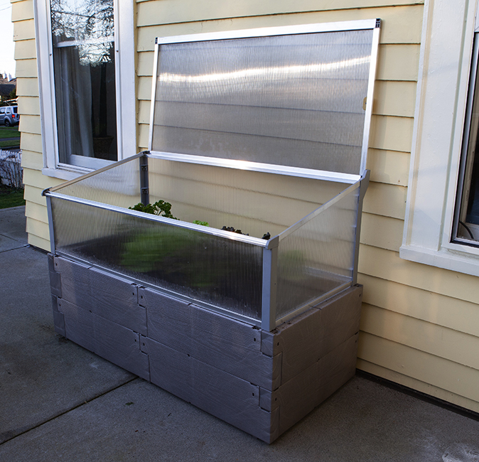 gray timber raised bed with cold frame against house fully open